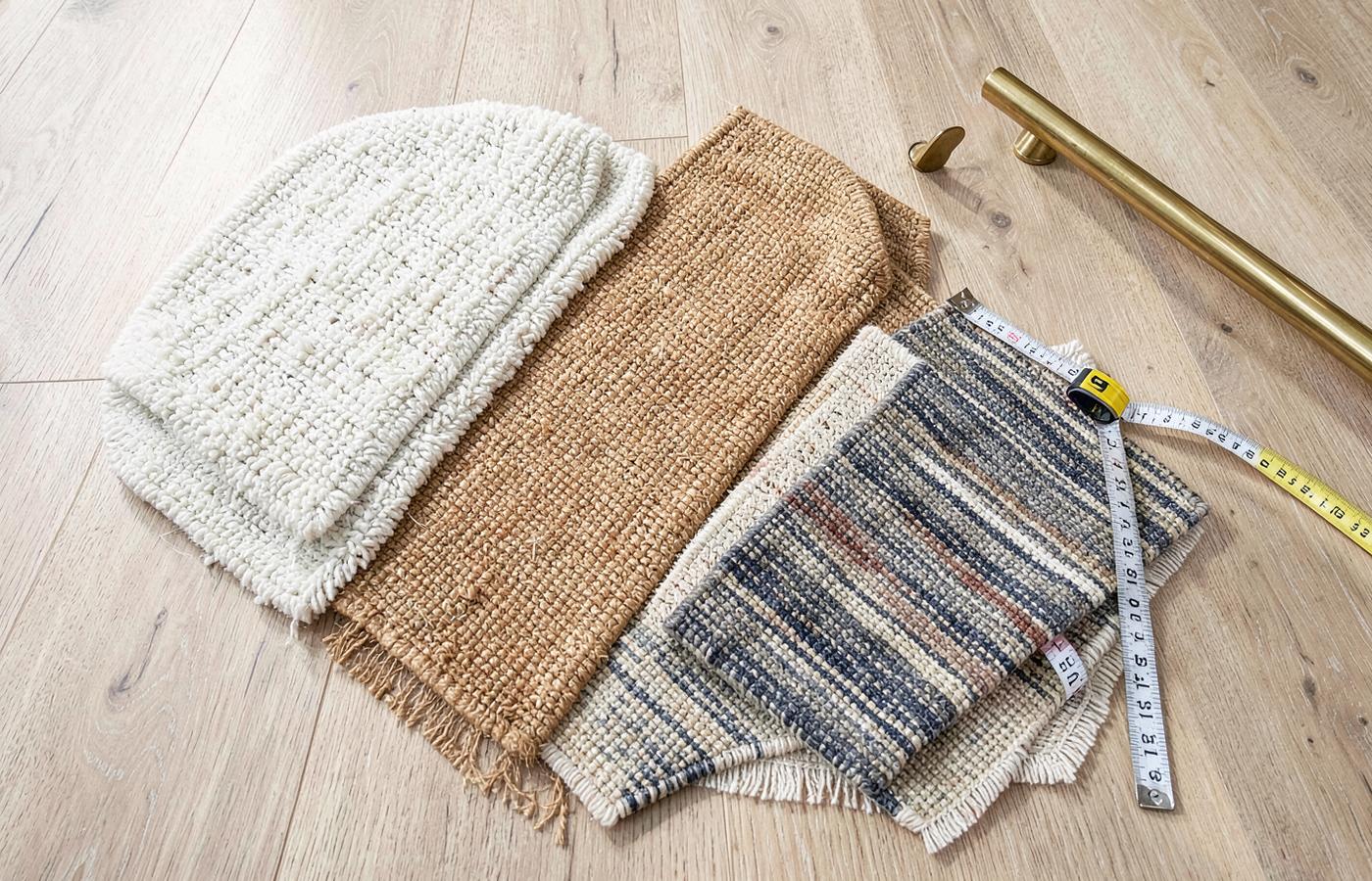 Carpet runner samples in wool loop, sisal, jute and striped flatweave laid on an oak floor with a tape measure and brass stair rod